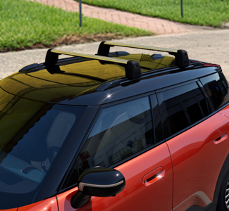 Nahaufnahme vom schwarzen Dach des orangenen Autos mit zwei montierten Grundträgern (Dachträgern).