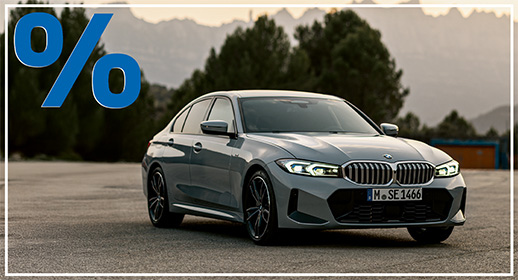  Ein hellgrauer BMW 318i Sedan von vorne schräg dargestellt, mit einer kleinen weißen Plakette "BMW 318i" am Kühlergrill, auf einem blauen Hintergrund. Das Bild präsentiert ein Neuwagenangebot für dieses Modell.