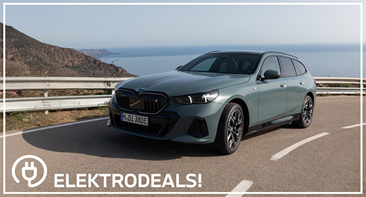 "Dreiviertel-Vorderansicht einer hellgrauen BMW i5 Elektro-Limousine mit Kennzeichen 'MDY 237E', parkend auf Asphalt vor einer Betonmauer. Mit 'Elektrodeals!'-Logo."