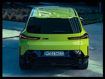Das Heck des BMW XM 50e ist geprägt durch die vertikal angeordneten Doppelendrohre, die flachen LED-Rückleuchten und das zentral platzierte XM-Logo in Schwarz.