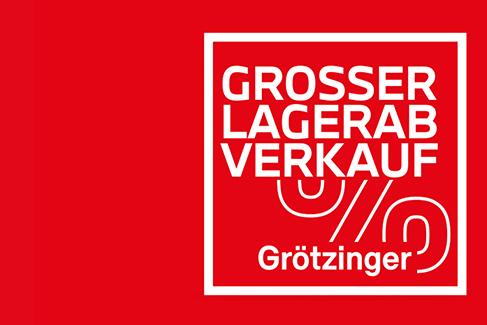 Auch dieses Bild ist eine Werbegrafik auf einem leuchtend roten Hintergrund. Ein weiß eingerahmtes Quadrat auf der rechten Seite zeigt in weißen Großbuchstaben den Text „GROSSER LAGERAB VERKAUF“. Darunter sind weiße, geschwungene Linien eingefügt, die abstrakte Räder oder ein Prozentzeichen andeuten. Im unteren Teil des Quadrats steht in weißer Schrift der Name „Grötzinger“. Die Grafik ist klar und werbewirksam gestaltet.