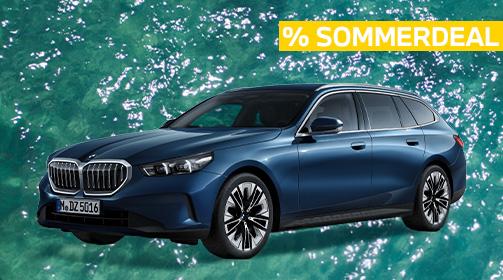 Ein dunkelblauer BMW 520i Touring steht auf einem leuchtend türkisen, leicht bewegten Wasserhintergrund. Das Fahrzeug ist leicht von vorne links aufgenommen, wodurch die Frontpartie mit dem markanten Kühlergrill und die gesamte linke Fahrzeugseite gut zu erkennen sind. Oben rechts im Bild ist ein gelber Balken mit der Aufschrift „% SOMMERDEAL“ in Großbuchstaben platziert. Der Kombi wirkt elegant und sportlich zugleich, mit modernen Felgen.