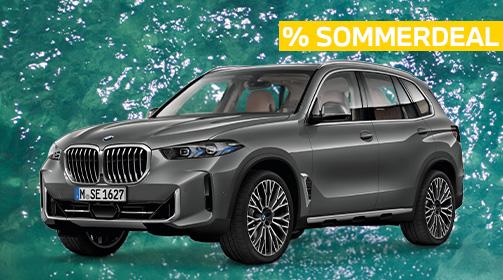 Ein anthrazitfarbener BMW X5 xDrive30d SUV steht prominent vor einem türkisfarbenen, leicht bewegten Wasserhintergrund. Das Fahrzeug ist leicht von vorne links aufgenommen, sodass die markante Frontpartie mit dem großen Kühlergrill und die gesamte linke Seite des Wagens mit seinen großen, komplexen Felgen gut sichtbar sind. Im oberen rechten Bildbereich ist ein leuchtend gelbes Banner mit der Aufschrift „% SOMMERDEAL“ in Großbuchstaben zu sehen. Die Innenausstattung in hellem Leder ist durch die Fenster leicht erkennbar.